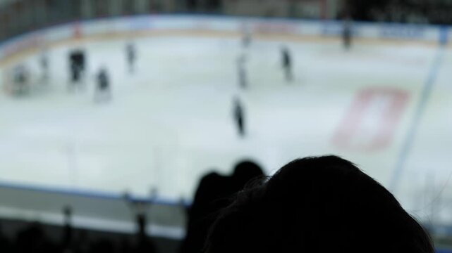 Silhouette of hockey fan celebrating goal on arena stands with blurred rink, ice hockey match festive atmosphere