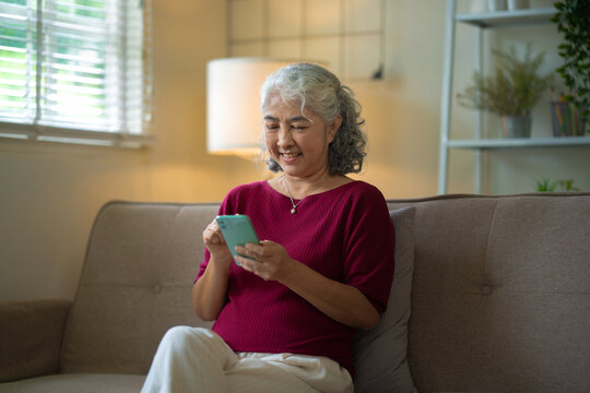 A relaxed senior woman enjoys online communication through social media on smartphone - Powered by Adobe