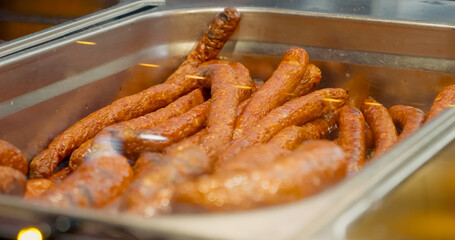 Sizzling sausages grilling with golden brown exterior, releasing enticing aromas while cooking over...