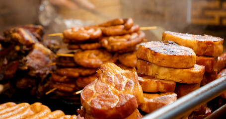 Street food market revealing succulent grilled pork, sizzling with appetizing aroma and ready for...