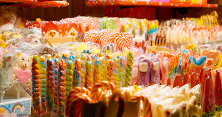 Explore a vibrant display of sweets and lollipops at a bustling Christmas market, where festive...