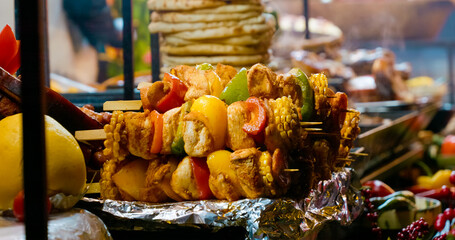 Delicious skewers of grilled chicken, peppers, corn, and potatoes, steaming hot at a street food market stall