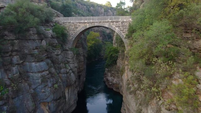 The K&ouml;pr&uuml;&ccedil;ay River flowing beneath Oluk Bridge. The historic Roman bridge, nestled among the steep cliffs of K&ouml;pr&uuml;l&uuml; Canyon National Park, surrounded by lush green landscapes.