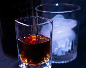 Close up of a shot glass that is almost full of brown liquor. 