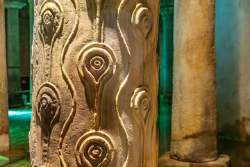 Ancient column with intricate carvings in an underground chamber