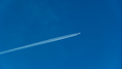 Avión comercial dejando una estela de vapor en un cielo azul
