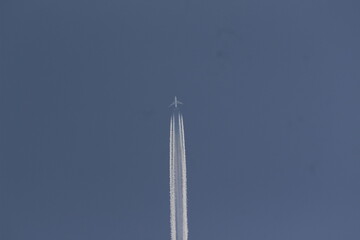 Boeing 747 jumbo jet passing by in high speed leaving contrails behind.