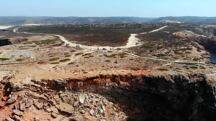 Dramatic coastal overview, remote rugged coastline with trails and sunlit sandstone formations. Media - Powered by Adobe