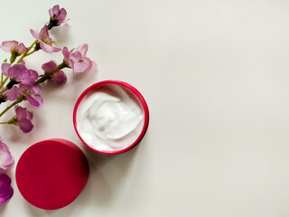 An open jar of skincare cream is placed on a light surface. 