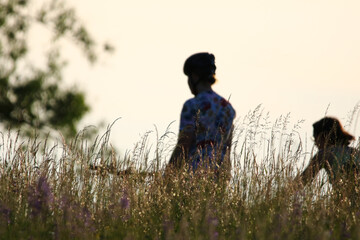 Two people riding bikes through tall grass at sunrise near Regensburg