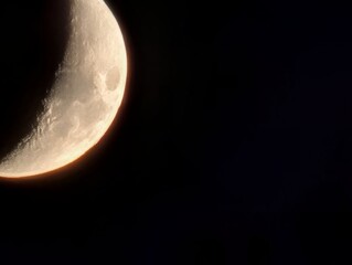 A captivating crescent moon hanging in the night sky. The moon has a bright glow and the darkness enhances the detail