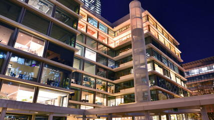 Modern office building in city center illuminated at night. Rows of lit windows against the architectural grid of a modern facade.