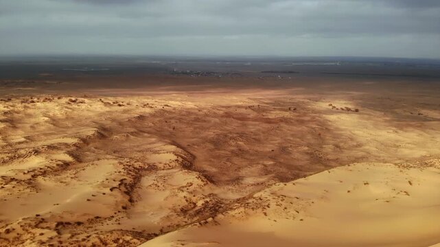 aerial perspective illustrating desolate sandy plains with sparse vegetation and geological formations . Media
