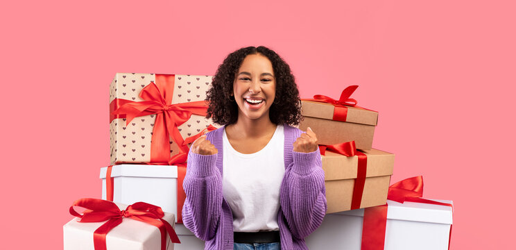 A woman stands happily among beautifully wrapped gifts, expressing joy and anticipation. The vibrant background enhances the festive mood, perfect for celebrating special moments.