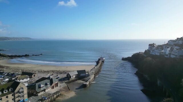 
Looe, Cornwall, England: DRONE VIEWS: The drone flies over rooftops towards the Looe estuary, Looe beach, Banjo Pier and the sea. Looe is an ancient fishing port and popular UK holiday destination.