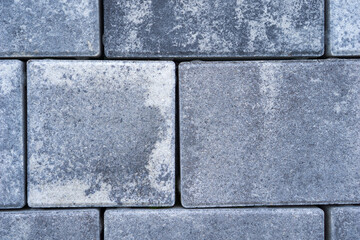 abstract view of rectangular grey interlocking paving bricks showing worn rough texture and dark color tightly fitted together forming a pattern, concept of construction, urban design, hardscaping