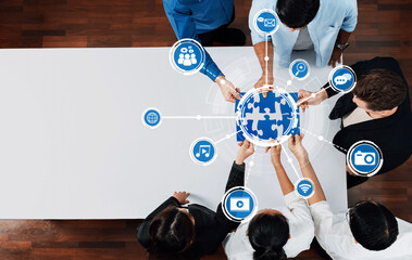 A diverse group of professionals engages over a puzzle globe, symbolizing collaboration and connections in the digital world. Icons highlight technology and communication themes. Amity