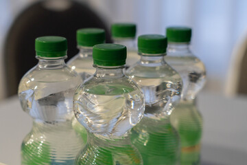 Bottled water with green caps arranged on a table, showcasing clear liquid and textured plastic, ideal for hydration and refreshment in various settings