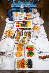 Overhead view of lavish breakfast spread with pastries, fruit, cheese and nuts on white table
