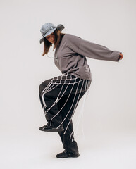 Female hip-hop dancer in gray street style outfit dancing in studio