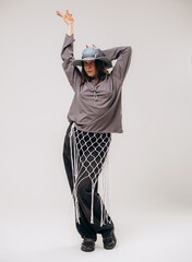 Female hip-hop dancer in gray street style outfit dancing in studio