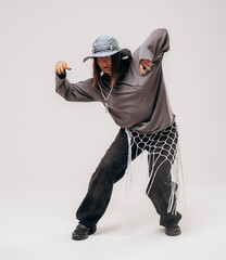 Female hip-hop dancer in gray street style outfit dancing in studio