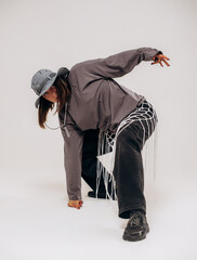 Female hip-hop dancer in gray street style outfit dancing in studio