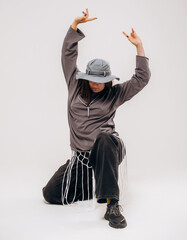 Female hip-hop dancer in gray street style outfit dancing in studio