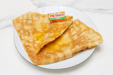 Cr&ecirc;pe au beurre et sucre sur une assiette blanche, table en marbre, dessert fran&ccedil;ais