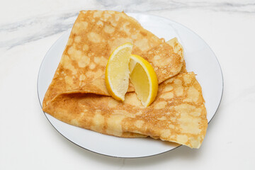 Crêpe au sucre et citron sur une assiette blanche, table en marbre, dessert français