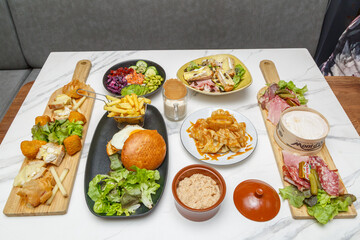 Assortiment de plats traditionnels français sur une table en marbre — charcuterie, fromages, salade de chèvre chaud et riz au lait. Bistro. 