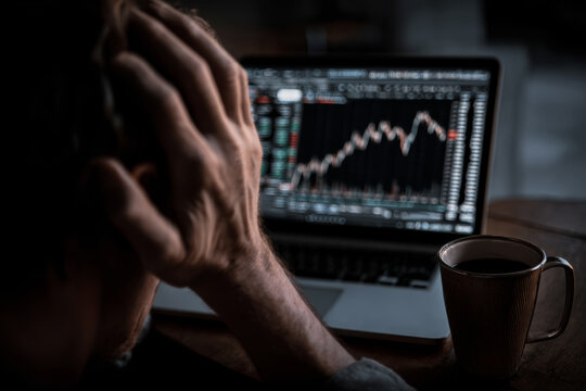 Person looking at financial chart on laptop with coffee