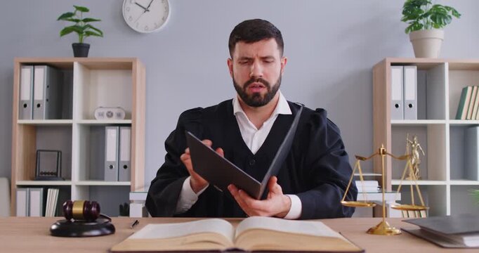 Portrait of man judge reading verdict and striking gavel or mallet in courtroom during law session, focusing on sentence and judgment in a professional setting with a sense of authority and legal.