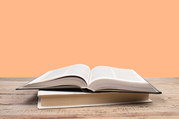 open book. Composition with hardback books, fanned pages on wooden deck table and orange background. Books stacking. Back to school. Copy Space. Education background.