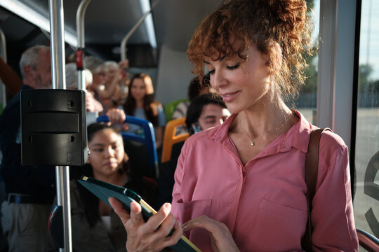 Woman commuter using tablet on public transport bus - Powered by Adobe