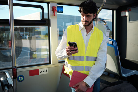 Worker commuting on public transport checking smartphone