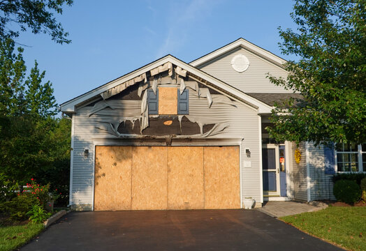 House with severe fire damage in garage area. Plywood is covering window and garage door areas
