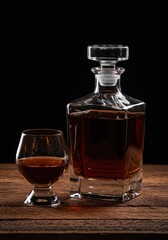 A crystal decanter holds a rich amber distilled spirit resting on a rustic wooden surface, highlighting clarity and color, premium, bottle, transparent