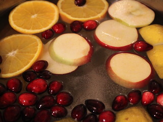 Sliced apples, orange, lemons cranberry, in boiling water. Autumn and winter are the season for hot drinks