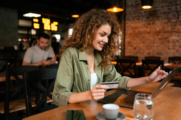 Young woman enjoying coffee and shopping online in a cozy cafe during the afternoon