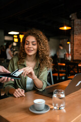 Young woman enjoying coffee while using a laptop in a cozy cafe setting