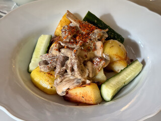 Creamy mushroom sauce with roasted potatoes and cucumber. Warm comfort food, balance of taste, and homely dining experience in natural light Close-up
