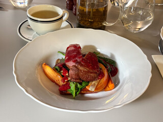 Meat with vegetables and berry sauce on a white plate. Culinary craftsmanship, contrast of colors, and fine dining mood through modern plating.