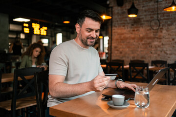 Man using credit card to make online purchase at cafe during morning coffee