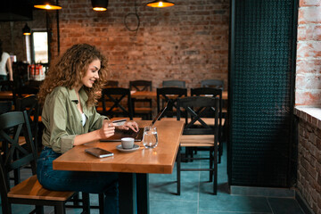 Young woman working on laptop in cozy cafe during afternoon in a lively location