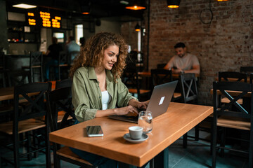 Young woman working on laptop in modern cafe with cozy atmosphere during afternoon hours