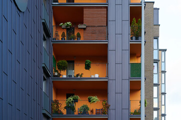 Obraz premium modern apartment balconies with colorful facades featuring plants and outdoor furniture. urban living, vertical gardens, and contemporary architecture highlighted in vibrant city scene.