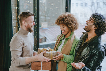 A multi ethnic group of friends hugging and giving each other craft paper wrapped gifts