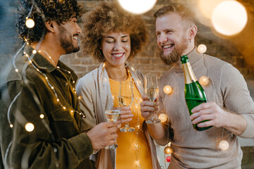A group of friends raising glasses of champagne and one of them making a toast indoor