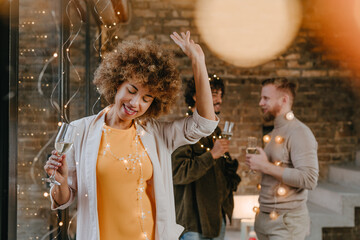 A group of friends dancing with raising glasses of champagne on the Happy New Year party